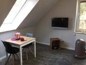 Zimmer mit einem Tisch und einem TV im Dachgeschoss in der Unterkunft Apartment Marit in Norden