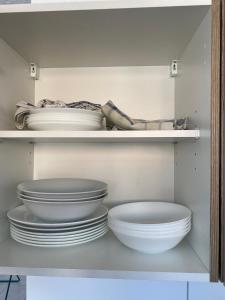 um armário branco com pratos e tigelas dentro em nJoy! EXPO Studio & Zentral - Stuttgart Flughafen & Messe - perfekt für Work & Travel em Filderstadt