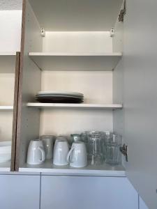 a kitchen cabinet with white cups and utensils at nJoy! EXPO Studio & Zentral - Stuttgart Flughafen & Messe - perfekt für Work & Travel in Filderstadt