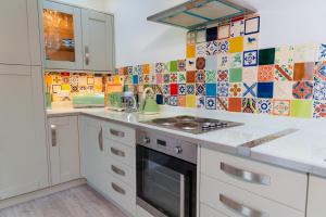 a kitchen with white cabinets and a stove top oven at Polrunny Farm Sloe Cottage with a sea view in Boscastle