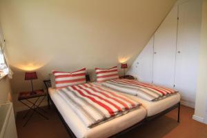 una camera con 2 letti con cuscini a righe di Weitblick a Tinnum