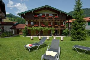 a house with two lawn chairs in front of it at Landhotel Maiergschwendt by Deva Hotels & Resorts in Ruhpolding