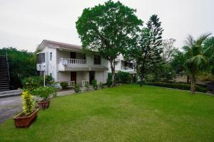 a house with a green lawn in front of it at EKO STAY - Tropical Beach Apartments in Mumbai
