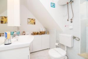 a white bathroom with a toilet and a sink at Apartman Neve in Dubrovnik
