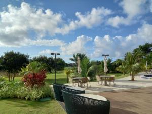 a patio with tables and chairs and palm trees at Flat Cantinho do Paraíso in Guarajuba
