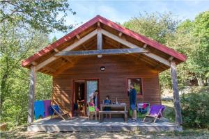 een familie buiten een blokhut met een tafel en stoelen bij Les Châtaigniers du Lac in Pourcharesse