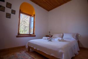 um quarto com uma cama branca e uma janela em Eremia Rustic House - Entire Villa in Pelion em Makrinitsa