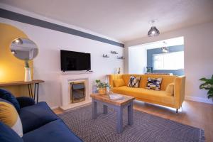 a living room with a yellow couch and a fireplace at Saltbox Properties- LARGE!! 3 bed, 3 bath house, parking, fast wifi, town centre location! sleeps 6 in Ashby de la Zouch