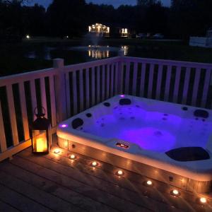 a jacuzzi tub on a deck at night at Juniper Lodge with Hot Tub in York