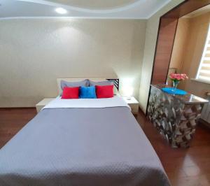 ein Schlafzimmer mit einem großen weißen Bett mit roten und blauen Kissen in der Unterkunft Уютная квартира класса ЛЮКС в городе Тараз in Taras