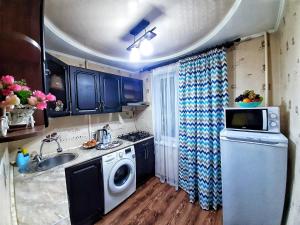 een kleine keuken met een wasmachine en een wastafel bij Уютная квартира класса ЛЮКС в городе Тараз in Taraz