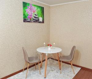 tavolo da pranzo con sedie e dipinto sul muro di Уютная квартира класса ЛЮКС в городе Тараз a Taraz