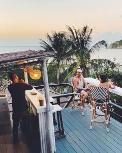 a group of people sitting at a table on a deck at Cookies Salad Resort in Salad Beach