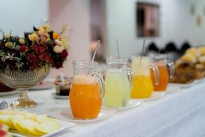 a table with several glasses of orange juice and fruits at Hotel Monte Carlo in Dourados