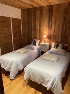 two twin beds in a room with wooden walls at Appartement dans chalet in Montgenèvre
