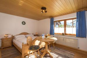 a bedroom with a bed and a table and a desk at Ferienhaus Am Steinbach in Ruhpolding