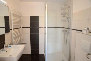 La salle de bains blanche est pourvue d'une douche et d'un lavabo. dans l'établissement La Mer Whg 01, à Wyk auf Föhr