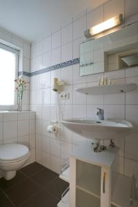 a white bathroom with a sink and a toilet at Haus Gud Hööb Whg 07 in Wyk auf Föhr