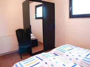 um quarto com um espelho, uma cama e uma cadeira em Bungalow 451 in Tossens em Tossens