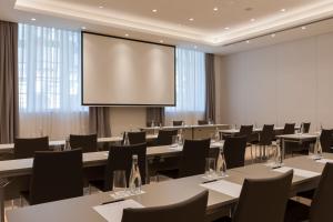a conference room with tables and chairs and a projection screen at Kozmo Hotel Suites & Spa - The Leading Hotels of the World in Budapest