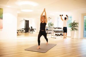 una mujer haciendo una pose de yoga en una clase de yoga en Hotel Frisia, en Leer