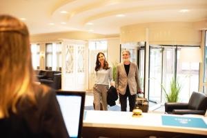 a man and a woman walking through a room at Hotel Frisia in Leer