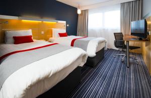 Holiday Inn Express London - Epsom Downs, an IHG Hotel في إبسوم: غرفة فندقية بسريرين ومكتب وتلفزيون