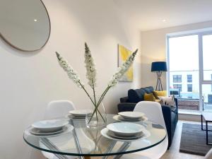a living room with a glass table with a vase of flowers at Elevate at Fleet Heights Apartment Seven in Fleet