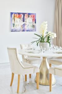 a white dining room with a white table and chairs at Contemporary and Spacious 2 BR in Bluewaters Island in Dubai