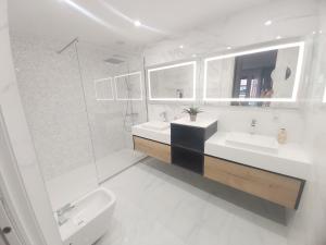 - une salle de bains blanche avec deux lavabos et une douche dans l'établissement San Antón Piso de lujo en pleno centro de Logroño, à Logroño