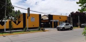 マラルグエにあるHotel El Nevado, Malargüe Mendozaの黄色い建物の前に駐車した白車