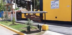 Hotel El Nevado, Malargüe Mendoza في مالارغي: مبنى اصفر مع قطار العاب على الشارع