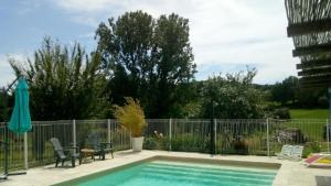 a swimming pool with two chairs and a fence at chambre namaste in Montcléra