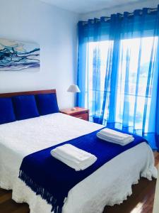 una camera da letto con tende blu e un letto con asciugamani di Apartamento Vitória a Praia da Vitória
