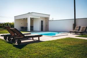 a pool with two lounge chairs and a house at olive tree house in Mostar