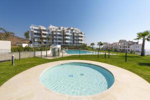 une piscine dans un parc avec un bâtiment en arrière-plan dans l'établissement Apartamento de lujo de 2 dormitorios, à Torrox Costa