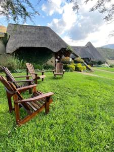 Dos sillas frente a una casa con techo de paja en Ithaba Falls Guest Farm Farm L59, Buffelsvley, Burgersfort, 1150, en Boerboomskraal