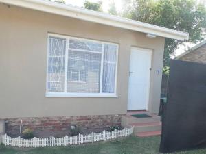 a white house with a window and a door at Heron Place sunny self-catering garden flatlet in Port Alfred