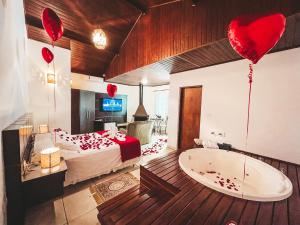 a bedroom with a bed and a tub with red heart balloons at Pousada Flor de Ipe in São Bento do Sapucaí