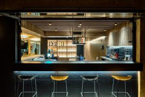 a bar with three stools in front of a kitchen at Hotel Delfín in Tossa de Mar