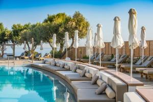 a swimming pool with lounge chairs and umbrellas at Enorme Teatro Beach in Amoudara Herakliou