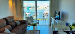 a living room with a couch and a view of a boat at Anacasa Puerto Explanada Cervantes AP1102 in Denia