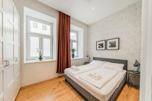sypialnia z łóżkiem z białymi prześcieradłami i dwoma oknami w obiekcie ZEUS Design Apartments Herz w Wiedniu