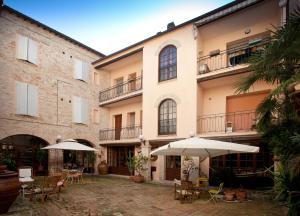 une cour avec des tables et des parasols en face d'un bâtiment dans l'établissement Relais B&B Corte Dei Turchi, à Longiano