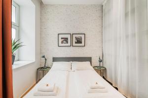 biała sypialnia z łóżkiem i dwoma stołami w obiekcie ZEUS Design Apartments Herz w Wiedniu