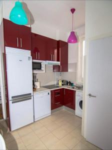 une cuisine équipée d'appareils rouges et blancs et de placards violets dans l'établissement Apartamento Piamonte, à Madrid