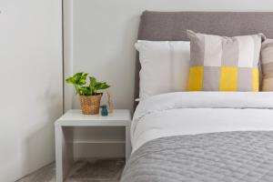 łóżko z żółto-białą poduszką i stolikiem. w obiekcie Camden Home - Barracks Properties w Londynie