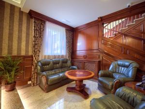 ApartHotel Hubertus في بياويستوك: غرفة معيشة مع كراسي جلدية وطاولة