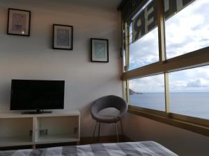a bedroom with a tv and a chair next to a window at Principado Marina II in Benidorm