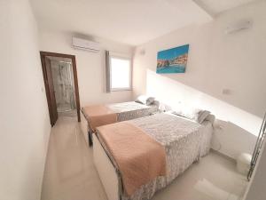 Cette chambre blanche dispose de 2 lits et d'une fenêtre. dans l'établissement Sliema Ferries Apartment, à Sliema